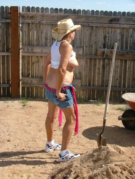 Older blonde Adonna plants her shovel in a pile of sand before disrobing 85441747