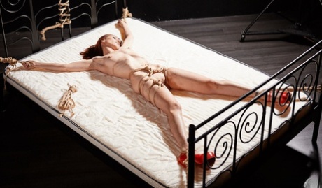 Redheaded girl is suspended and tied to a bed in red heels 39358335