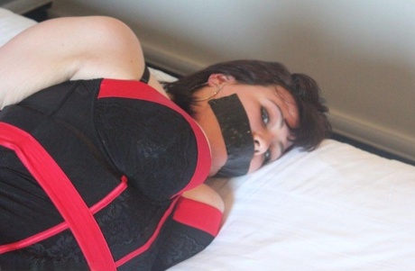 Caucasian woman is silenced with duct tape while tied up on a bed in lingerie 99088271