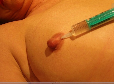 Naked blonde has her nipples pierced with a hypodermic needle 97255989