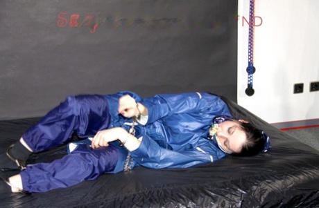Caucasian girl struggles while ball gagged and restrained in nylon rainwear 26309009