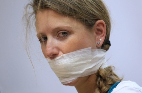 Caucasian female is silenced with a gag while tied to a chair in bare feet 68281794