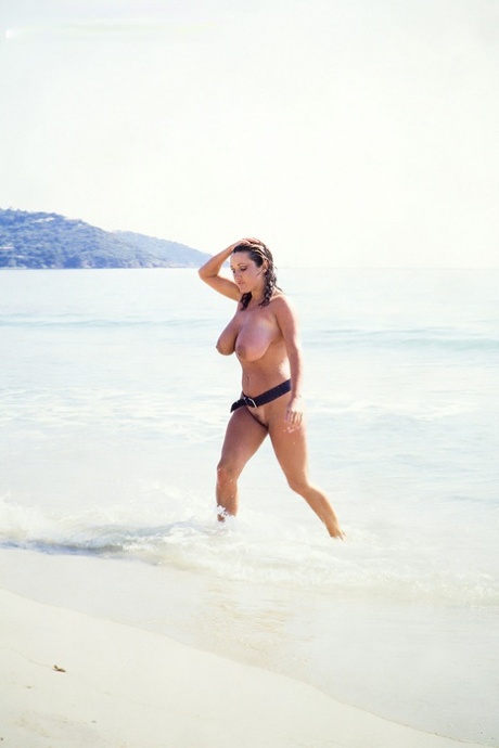 Sexy MILF Stacy Owen covers her big tits in sand on a beach 22975097