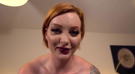 Tattooed redhead exposes her big tits in latex wear before riding a sex toy 36459183