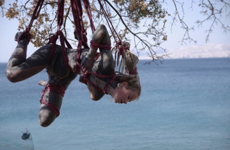Tattooed girl Anuskatzz is suspended by rope from a tree next to the ocean 21976468