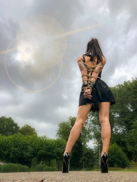 Asian chick Flawless Meow wears a neck collar with her arms bound in a park 29819748