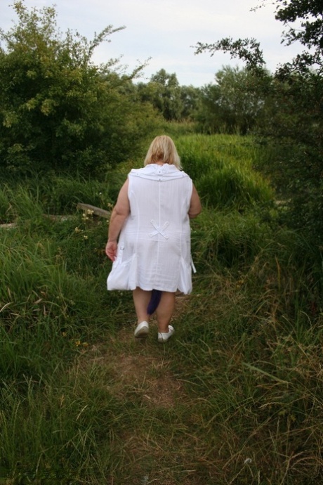Fat British lady Lexie Cummings exposes herself on a bench in a field 73928782
