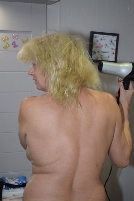 Naked older blonde Dimonty blow dries her hair before donning stockings 19746509
